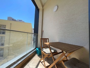 Un balcone con tavolo e sedie in legno, una finestra e un rilevatore di fumo montato a parete.