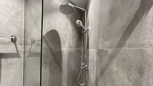 Moderni suihku, jossa on käsisuihkupää ja seinään asennettu hana.