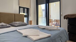 Hotellihuone, jossa on sänky, tuoli, pöytä ja parveke.