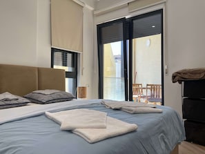 Una camera d'albergo con un letto, una sedia, un tavolo e un balcone.