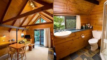 A wooden cabin interior with a dining area, a bathroom with a sink and toilet, and a view through a glass door.