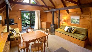 A cozy cabin interior with a wooden dining area, a sofa, and a fireplace.