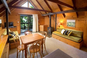 A cozy cabin interior with a wooden dining area, a sofa, and a fireplace.