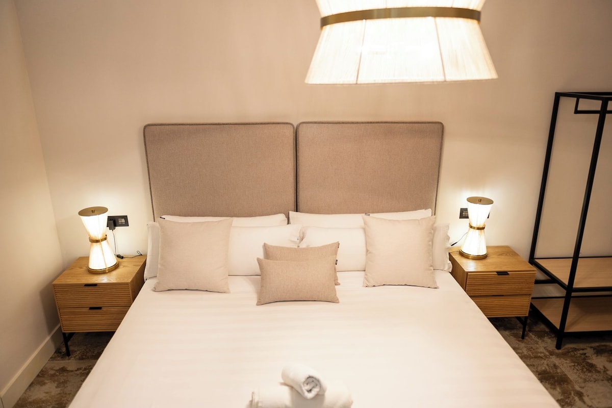 Ein Hotelzimmer mit einem großen Bett, zwei Nachttischen, einer Stehlampe und einer Deckenleuchte.