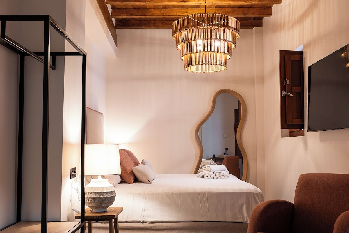 Ein Schlafzimmer mit Bett, Nachttisch, Lampe, Stuhl und Spiegel an der Wand.