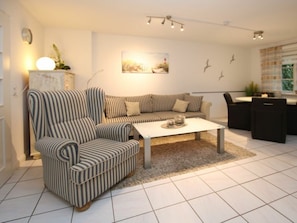 A modern living room with striped furniture, a coffee table, and a dining area with chairs. - 2 - Rungholtstrasse 3c (Wyk auf Foehr)