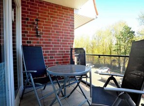A balcony with a brick wall, a round table, and two chairs. - 4 in the House Strandlauferweg 10 (St. Peter-Ording)