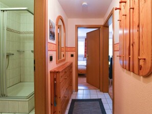 A hotel bathroom with a shower, a wooden vanity, and a mirror. - 4 in the House Strandlauferweg 10 (St. Peter-Ording)