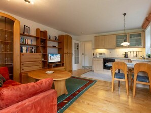 A modern living room with a wooden coffee table, red sofa, and a television. - Apartment 1 "dune Dream" (St. Peter-Ording)