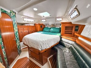A compact, well-lit interior with a bed, seating area, and storage cabinets. - Sailboat Stay + Resort Amenities (Key West)