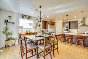 Une cuisine moderne avec un coin repas, des meubles en bois et des luminaires suspendus.