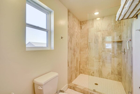 Een badkamer met toilet, douchecabine en raam.