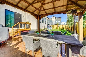 An outdoor patio with a covered seating area, a dining table, and a view of neighboring houses. - Park City Views! Hot Tub, Game Room & EV Charger (Park City)