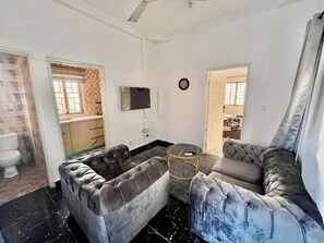 Ein Wohnzimmer mit einer Couch, einem Couchtisch und einem an der Wand montierten Fernseher.