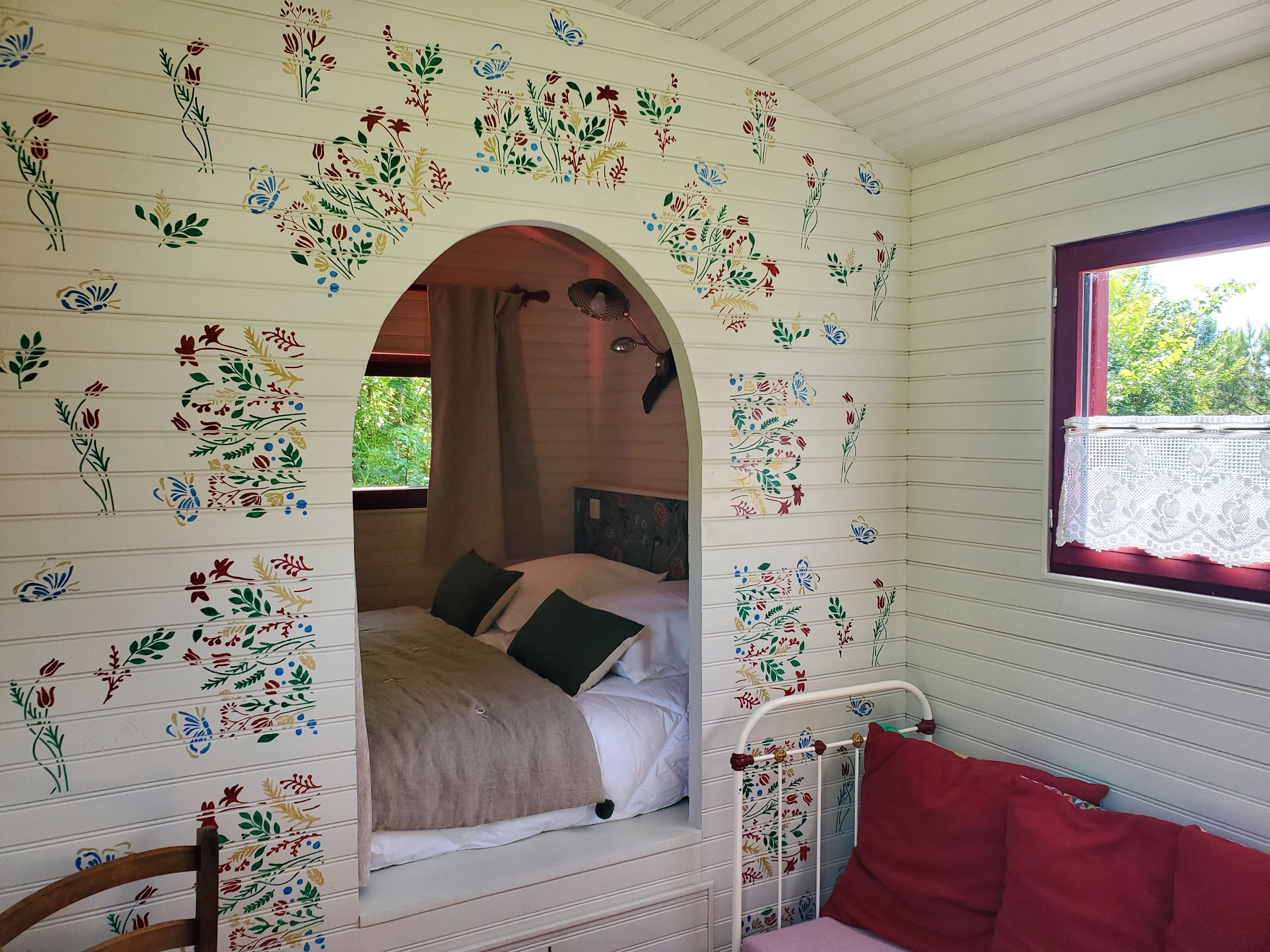 Een kamer met een bed, een raam en een decoratieve bloemenwand.