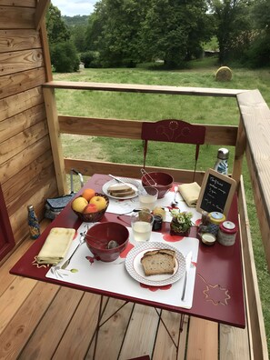 Un pontile in legno con un tavolo apparecchiato per un pasto, comprensivo di pane, frutta e condimenti.