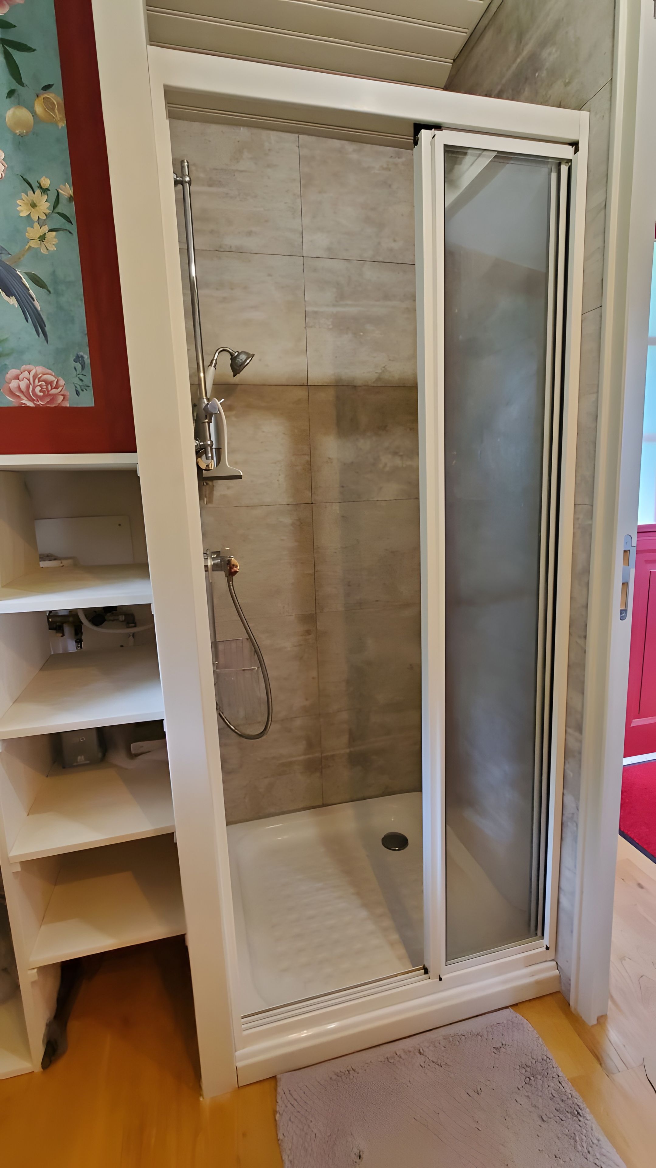 Une douche à l’italienne avec une porte en verre, un porte-serviettes et une étagère.