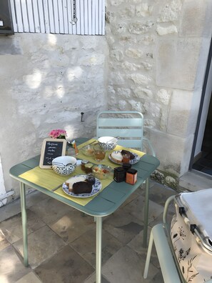 A table set with a variety of food items and a chalkboard menu, placed against a stone wall.