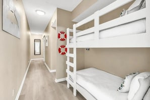 Ein Hotelzimmer mit einem Etagenbett, einer Holzleiter, einer weißen Matratze und zwei Rettungsflossen an der Wand.