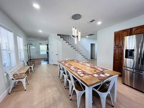 A spacious kitchen with a large wooden table, white chairs, a stainless steel refrigerator, and a staircase leading to another level. - Rustic Farmhouse with Hot Tub & Fire Pit Country Escape in Gatlinburg, Tennessee (Gatlinburg)