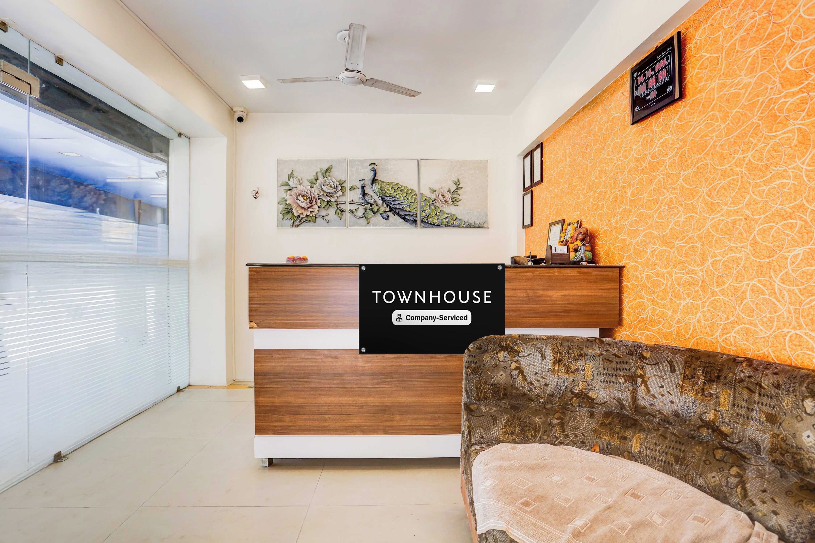 A reception desk with a sign reading 'TOWNHOUSE Company-Serviced' and a wall-mounted clock.