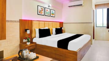 A hotel room with a wooden bed, bedside tables, a nightstand with a kettle and cups, and a window with curtains.