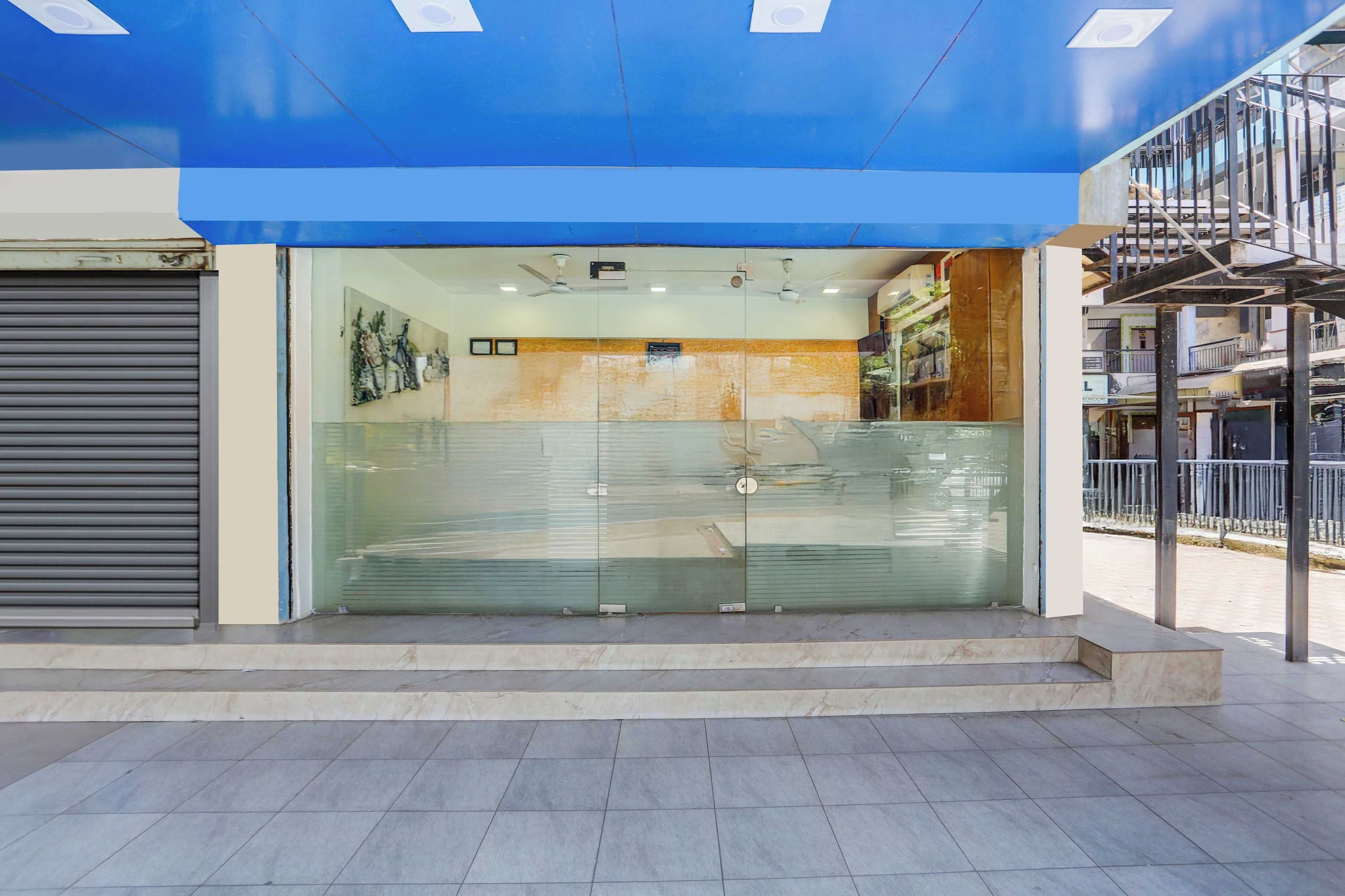 A building entrance with a blue awning, a closed shutter door, and a glass door with a security lock.