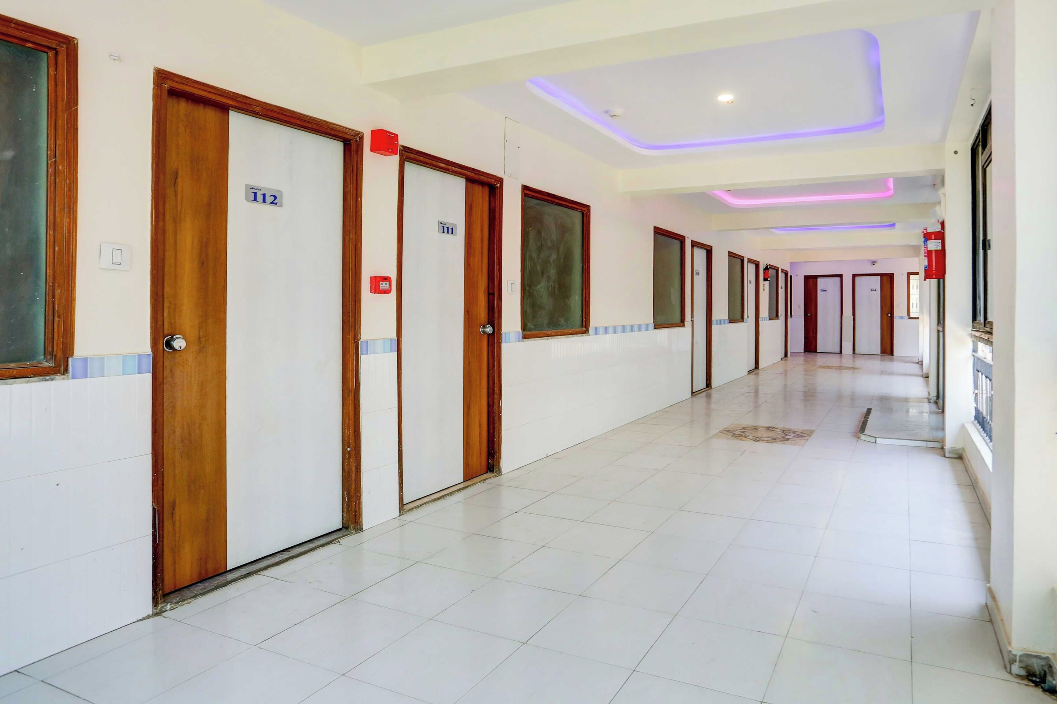 Un pasillo de hotel con puertas de madera, placas de habitaciones numeradas y suelo de baldosas.