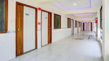 Un pasillo de hotel con puertas de madera, placas de habitaciones numeradas y suelo de baldosas.