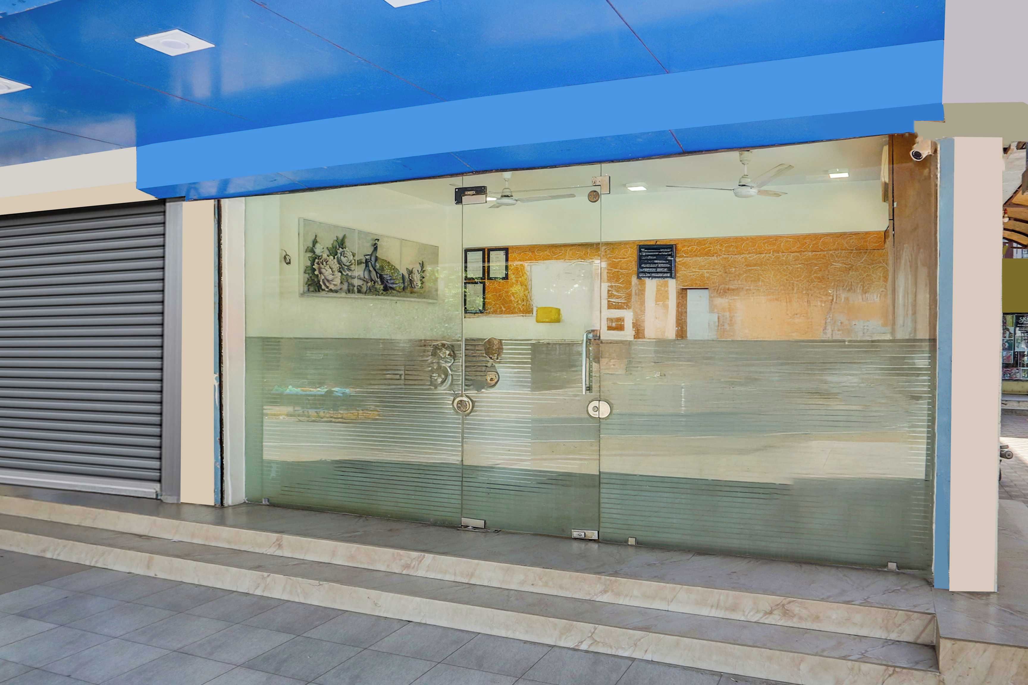 A building entrance with a glass door, steps leading up to it, and a blue ceiling.