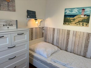 Ein Zimmer mit einem Bett, einer Kommode, einer Wandleuchte, einem Gemälde eines Leuchtturms und einem Schild mit der Aufschrift 'PREMIUM Vintage BISTRO'.