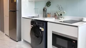 Une cuisine moderne dotée d’appareils électroménagers en acier inoxydable, de meubles blancs et d’un four encastré.