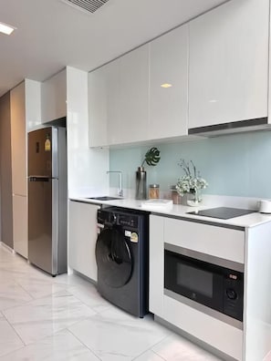 A modern kitchen with stainless steel appliances, white cabinetry, and a built-in oven. - Hyde Sukhumvit 11 at Nana BTS Station (Krung Thep Maha Nakhon)