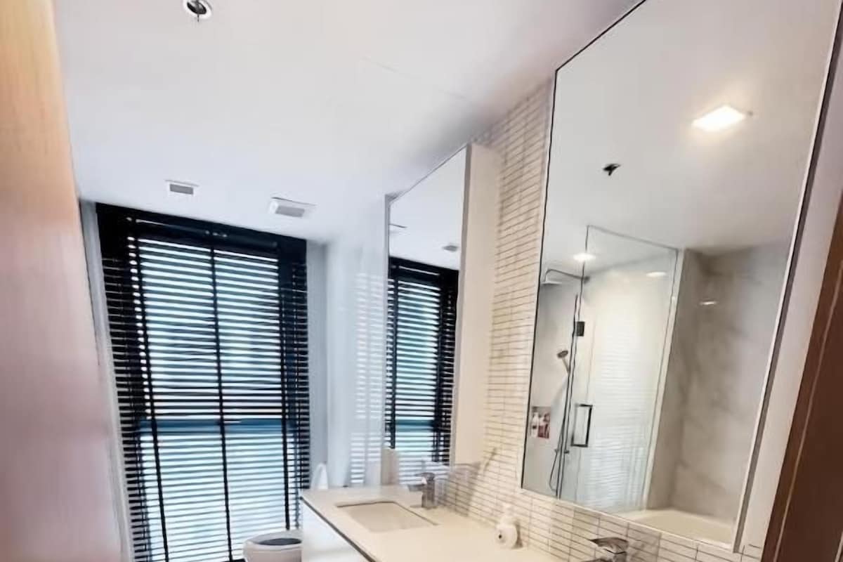 A modern bathroom with a large mirror, a sink, and a toilet.