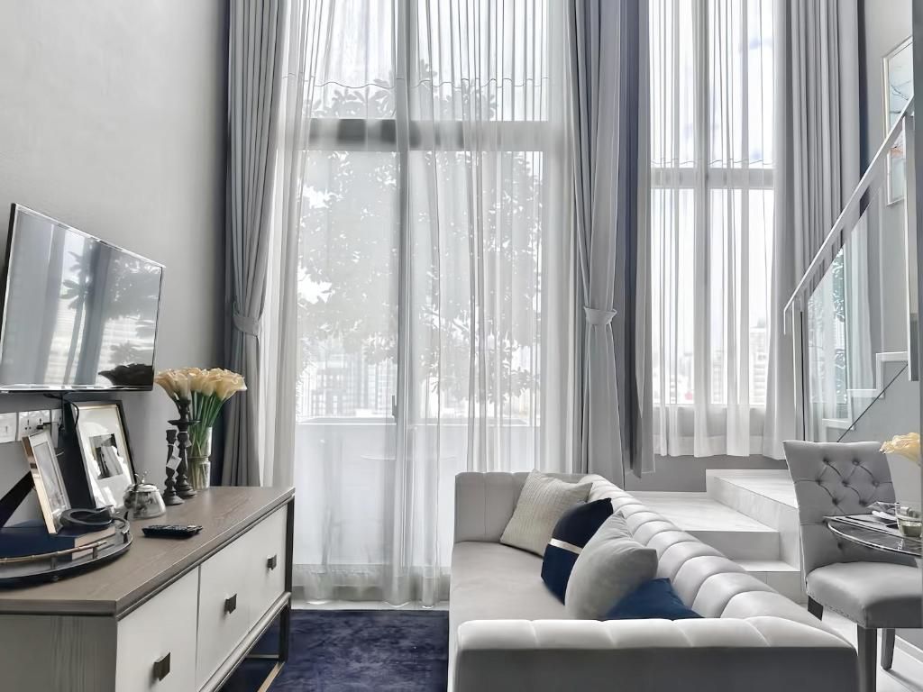 A modern living room with a sofa, a television, and a dining area with a table and chairs.