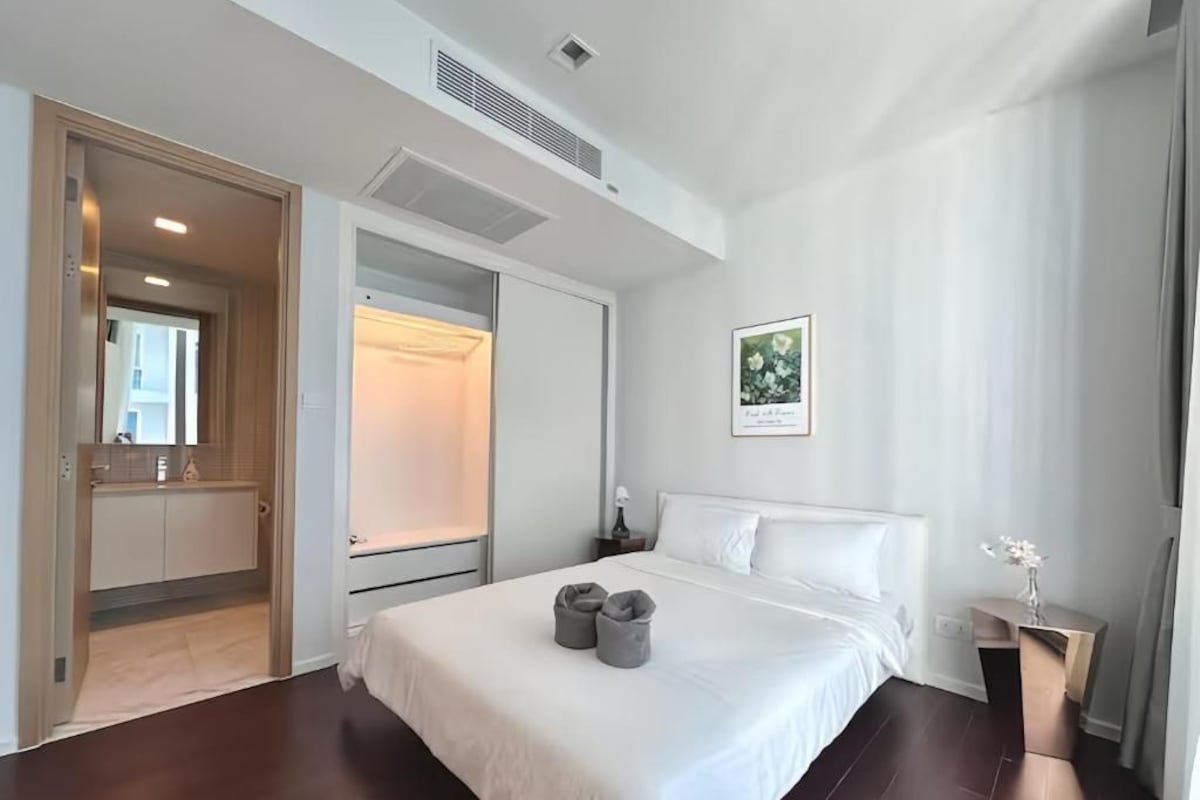 A hotel room with a large bed, a bedside table, a wardrobe, and a door leading to a bathroom.