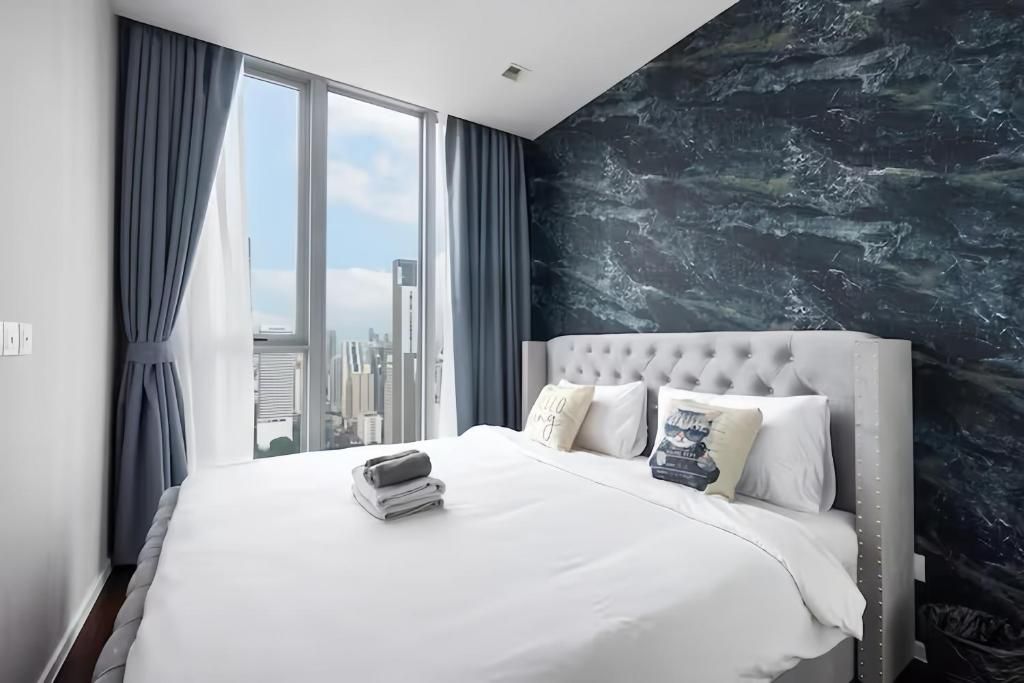 A modern hotel room with a large bed, city view, and a marble-patterned wall.