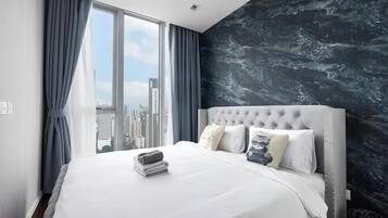 A modern hotel room with a large bed, city view, and a marble-patterned wall.