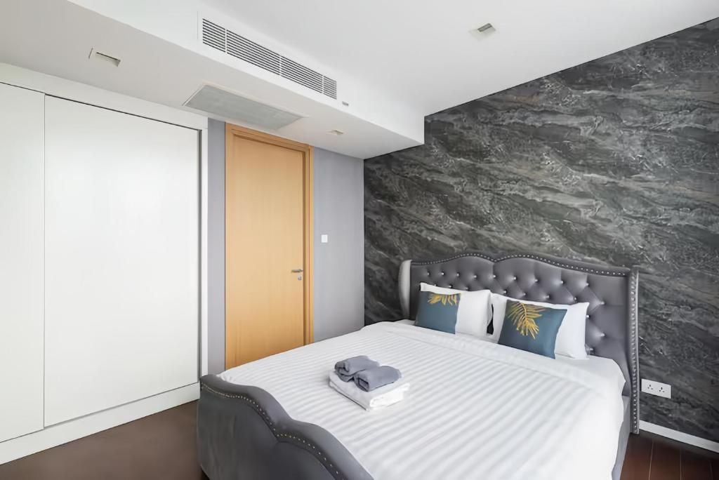 A modern bedroom with a bed, a wardrobe, and a marble wall.
