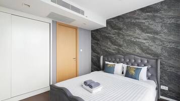 A modern bedroom with a bed, a wardrobe, and a marble wall.