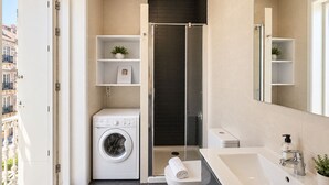 A modern bathroom with a built-in washing machine, a shower enclosure, and a large mirror. - Apartamentos Abrente - Porta Do Sol (Vigo)