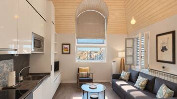 A modern kitchen with a built-in microwave, a dining area with a round glass table, and a sofa with decorative pillows.