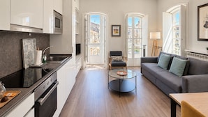 A modern kitchen with white cabinets, a black countertop, and a built-in oven. - Apartamentos Abrente - Porta Do Sol (Vigo)