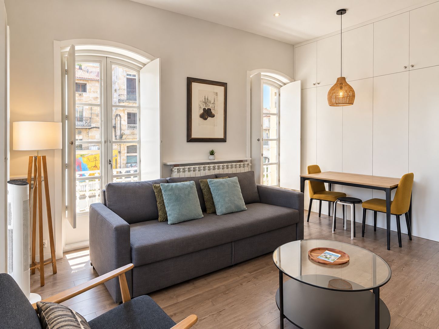 Ein modernes Wohnzimmer mit einer Couch, einem Glastisch und einem Essbereich mit Tisch und Stühlen.
