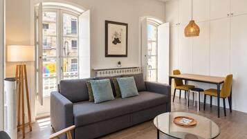 Ein modernes Wohnzimmer mit einer Couch, einem Glastisch und einem Essbereich mit Tisch und Stühlen.