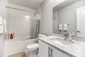 Et moderne badeværelse med badekar, toilet og et stort spejl.