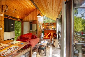 A wooden interior with a sofa, armchair, and table with color swatches, a mirror, and a shelf with various items. - Strae Cabin a Wooden Cabin in the Dalavich Countryside (Dalavich)
