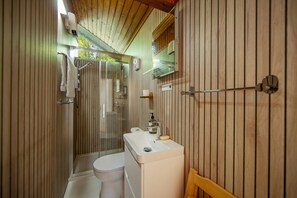 A bathroom with a wooden slat wall, a toilet, a sink with soap, and a towel rack. - Strae Cabin a Wooden Cabin in the Dalavich Countryside (Dalavich)
