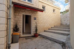 Ein Gebäude mit einer Steinfassade, einer roten Markise und einer Treppe, die zum Eingang führt.