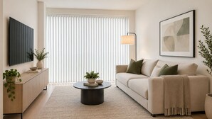 A living room with a sofa, a coffee table, a TV, and a lamp. - Toren Hotel & Suites (Toronto)